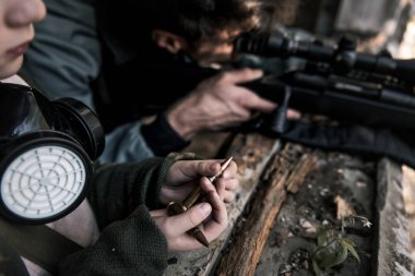 Elinde silah olan bir adamın yanında kurşunla gezen çocuk, kıyamet sonrası konsepti.