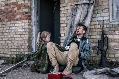 kid holding medical bandage near man sitting on ground, post apocalyptic concept clipart