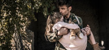 panoramic shot of man holding in arms and kissing kid with teddy bear, post apocalyptic concept clipart