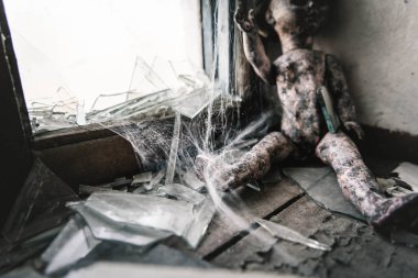 selective focus of cobweb near scary and burnt baby doll, post apocalyptic concept clipart
