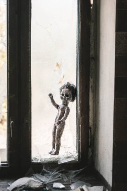 Kırık cam ve pencerenin yanındaki yanmış oyuncak bebek, kıyamet sonrası konsepti.
