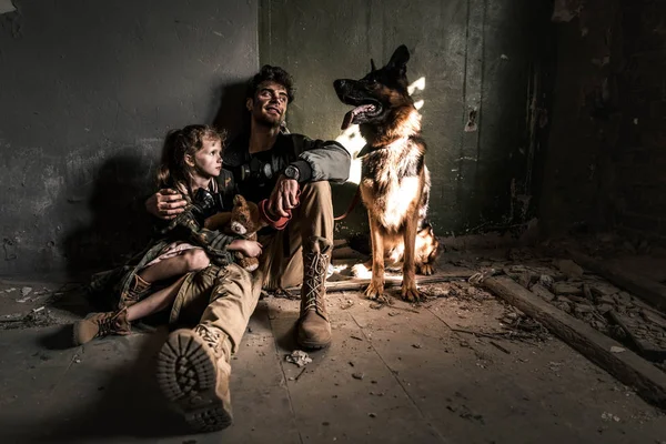 男人和小孩 泰迪熊和德国牧羊犬坐在地板上 世界末日后的概念 — 图库照片