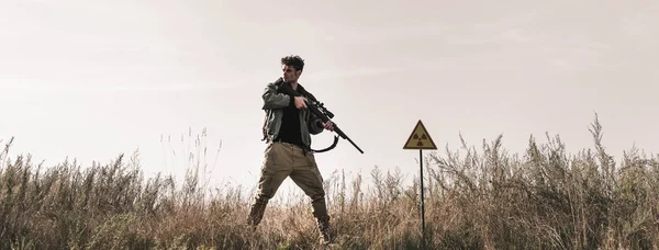 Tembakan Panorama Pria Tampan Memegang Pistol Dekat Simbol Beracun Lapangan — Stok Foto