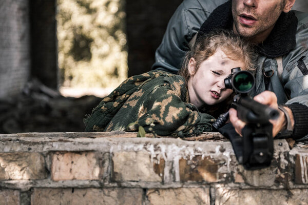 cropped view of man touching gun near kid, post apocalyptic concept