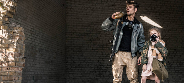 панорамный снимок человека, держащего фляжку рядом с ребенком с плюшевым мишкой
 