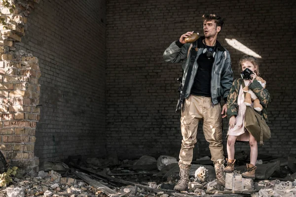 Knappe Man Met Veldfles Nabij Kind Met Teddybeer Post Apocalyptisch — Stockfoto