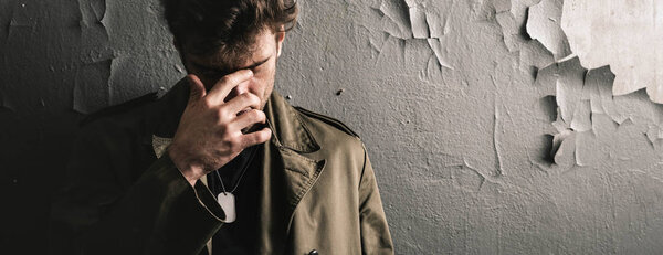 панорамный снимок человека, трогающего лицо, стоя у стены, постапокалиптическая концепция
