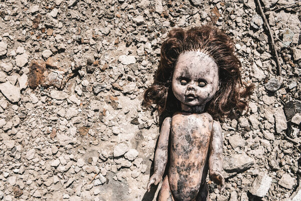top view of old and scary baby doll on ground, post apocalyptic concept
