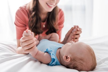 Mutlu bir kadının, küçük kızının elini tutup yatağa uzandığı görüntüler. 