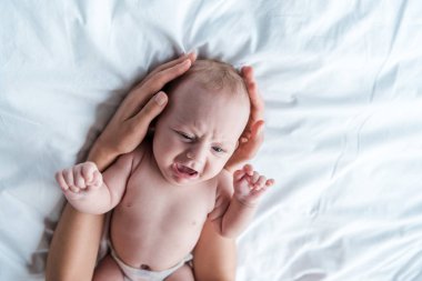 Annenin yatak odasında ağlayan bebek kızına dokunuşunun kırpılmış görüntüsü 