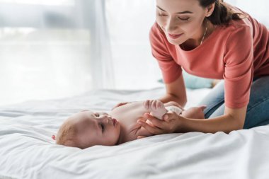 Güzel anne evde masaj yaparken tatlı bebeğe dokunuyor. 