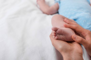 Küçük bebeğin bacağına dokunan şefkatli anne manzarası. 