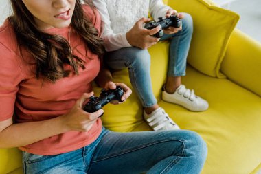 KYIV, UKRAINE - SEPTEMBER 4, 2019: cropped view of babysitter biting lips near kid while playing video game in living room 