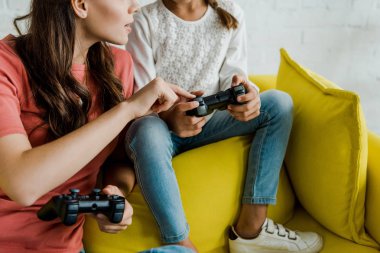 Kyiv, Ukrayna - 4 Eylül 2019: oturma odasındaki çocuğun yanındaki joystick 'i işaret eden bebek bakıcısının kırpılmış görüntüsü 