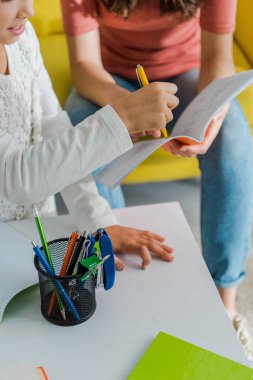 Bebek bakıcısının elinde kalemle sevimli bir çocuğun yanında defter tutması. 