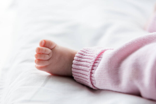 cropped view of infant baby lying on bed 