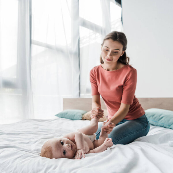 selective focus of cute infant looking at camera near mother 