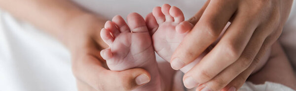 panoramic shot of woman doing massage while touching legs of infant baby 