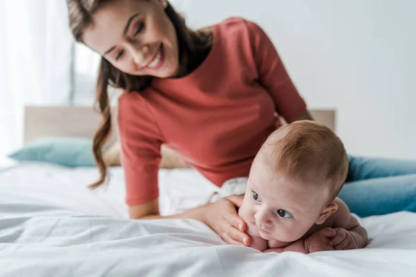 선별적으로 귀여운 아기를 침실에 아름다운 어머니 가까이에 시킨다 — 스톡 사진