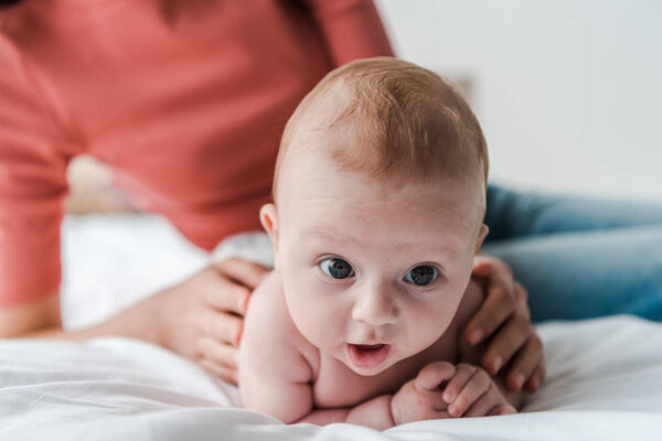 cropped view of woman touching baby daughter lying on bed at home 