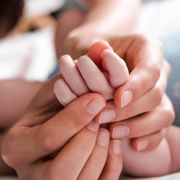 close up of mother holding hand infant daughter 