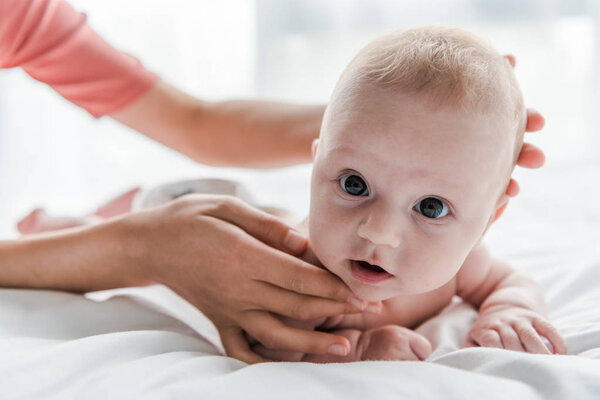 cropped view of mother doing massage to infant lying on bed at home 