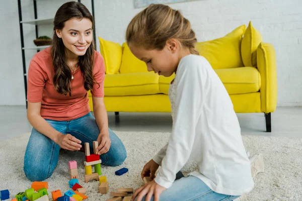 Enfoque Selectivo Niñera Mirando Niño Cerca Bloques Juguete Alfombra — Foto de Stock