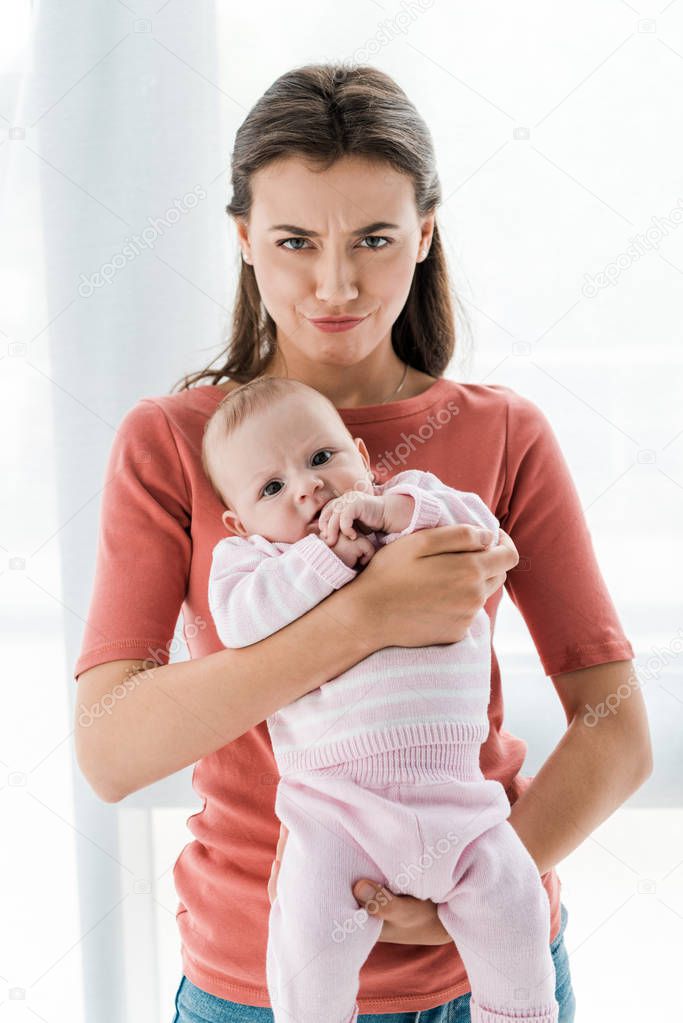 woman holding in arms adorable infant daughter at home 