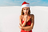 sexy žena v Santa klobouku a plavky při pohledu na kameru na pláži v Maledivách 