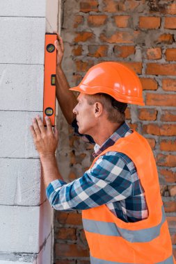 Miğferli orta yaşlı mimar beton duvar ölçer. 