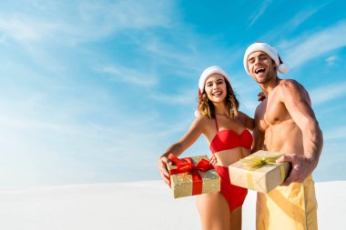 seksi ve gülümseyen kız arkadaş ve erkek arkadaş Maldivler sahilinde hediyeler tutuyorlar. 
