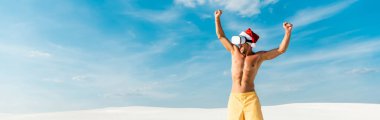 Sanal gerçeklik kulaklığıyla Noel Baba şapkalı seksi adamın Maldivler 'deki kumsalda evet jestini gösteren panoramik bir fotoğrafı. 