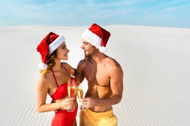 sexy girlfriend and boyfriend clinking with champagne glasses and hugging on beach in Maldives  clipart