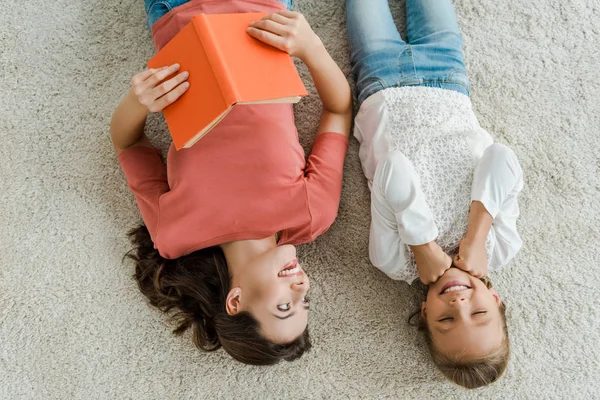 Top View Happy Babysitter Holding Book While Looking Kid Lying — Stock Photo, Image