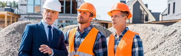Bauarbeiter Mit Helmen Stehen Neben Geschäftsleuten Anzügen Und Häusern — Stockfoto