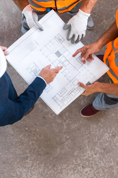 cropped view of constructors and businessman standing and holding blueprint 