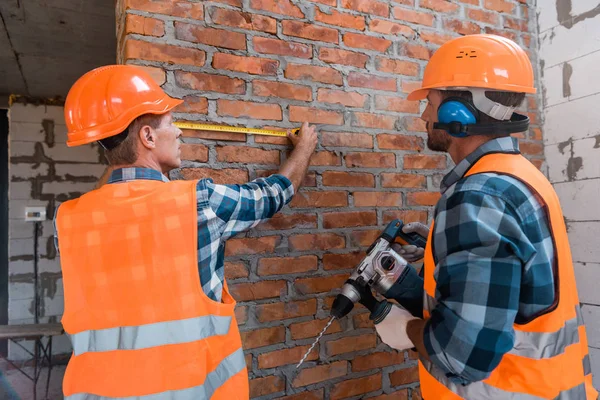 Construtor Parede Tijolo Medição Perto Colega Trabalho Com Broca Martelo — Fotografia de Stock