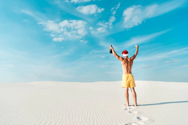 Вид Сзади Сексуального Мужчины Шляпе Санта Держащего Стекло Бутылку Пляже — стоковое фото