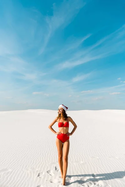 Sexy Uśmiechnięta Kobieta Santa Kapelusz Strój Kąpielowy Rękami Biodrach Plaży — Zdjęcie stockowe