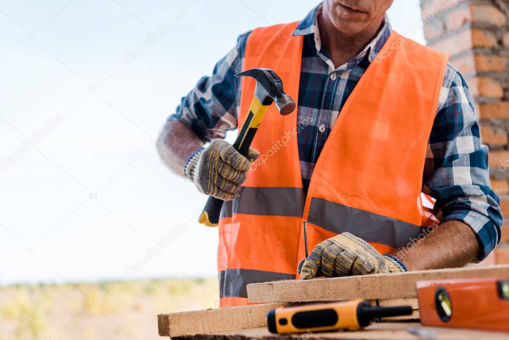 cropped view of middle aged constructor holding hammer 