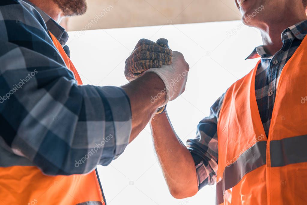 cropped view of constructor shaking hands with coworker 