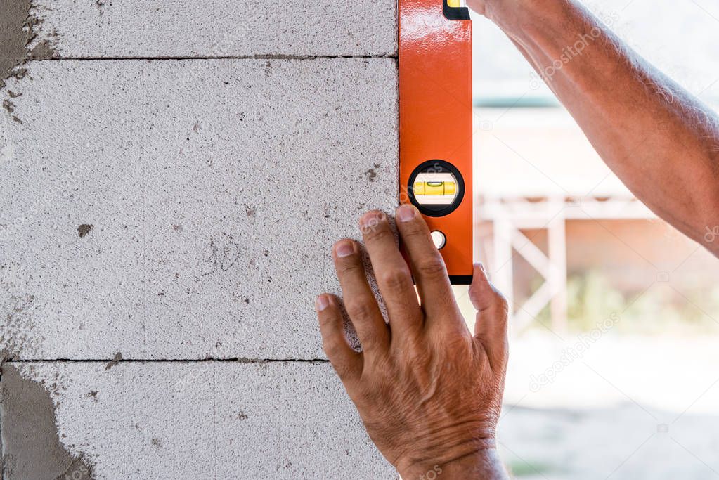 cropped view of mature man measuring concrete wall 