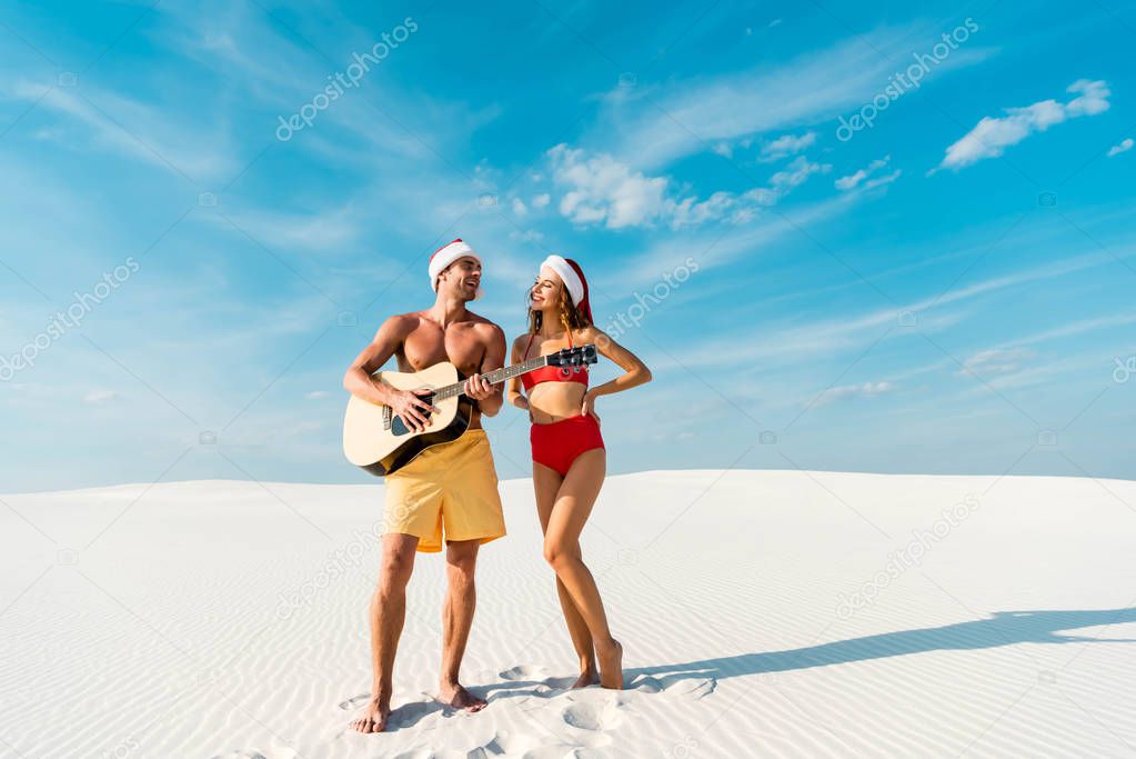 sexy girlfriend and boyfriend playing acoustic guitar on beach in Maldives 