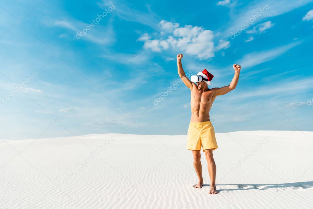 sexy man in santa hat with virtual reality headset showing yes gesture on beach in Maldives 