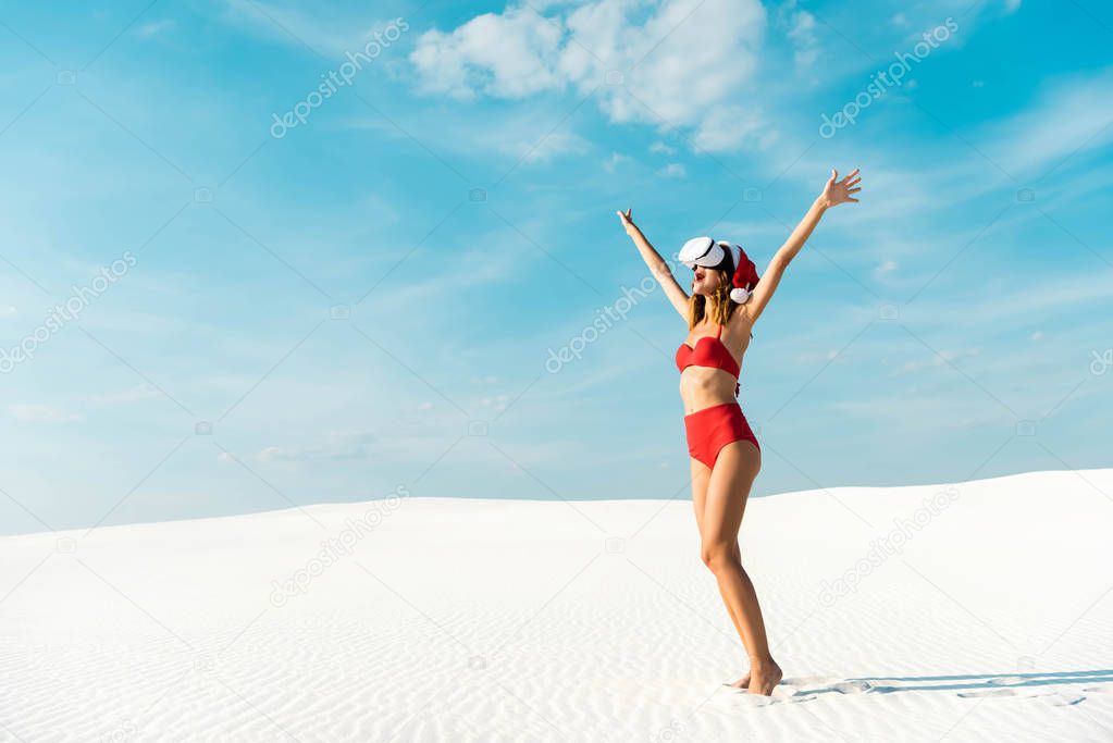 sexy woman in santa hat and swimsuit with virtual reality headset on beach in Maldives 