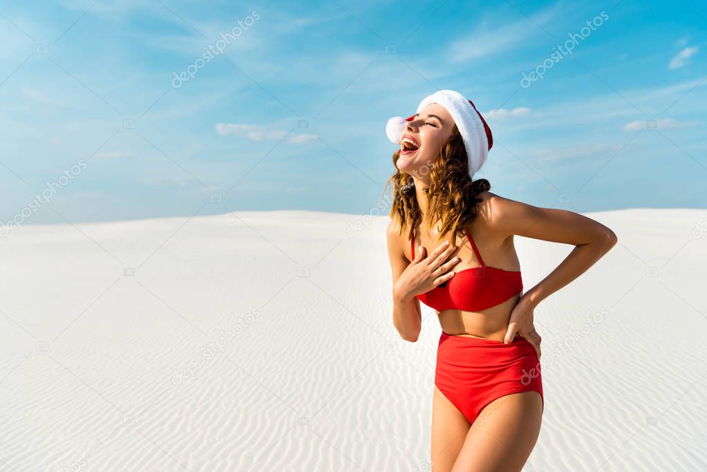 sexy and smiling woman in santa hat and swimsuit on beach in Maldives 