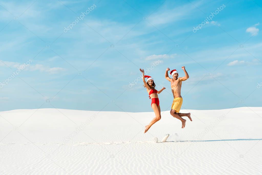 sexy girlfriend and boyfriend in santa hats jumping on beach in Maldives 