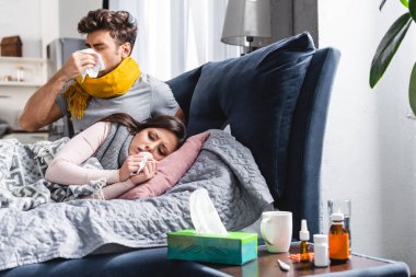 sick girlfriend and handsome boyfriend sneezing and holding napkins  clipart