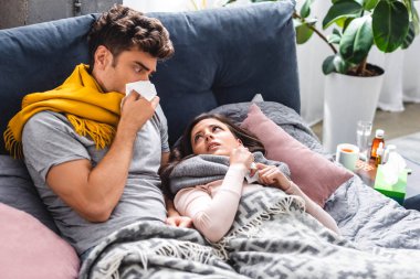 sick girlfriend and handsome boyfriend sneezing and holding napkins  clipart