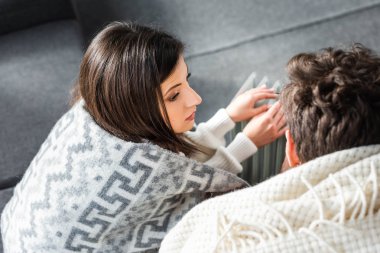 Isıtıcının yanındaki en boş ısıtmayla kaplı sevgili ve erkek arkadaşın yüksek açılı görüntüsü 